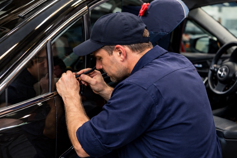 Serrurier automobile ouvrant une portière sans casse sur un parking